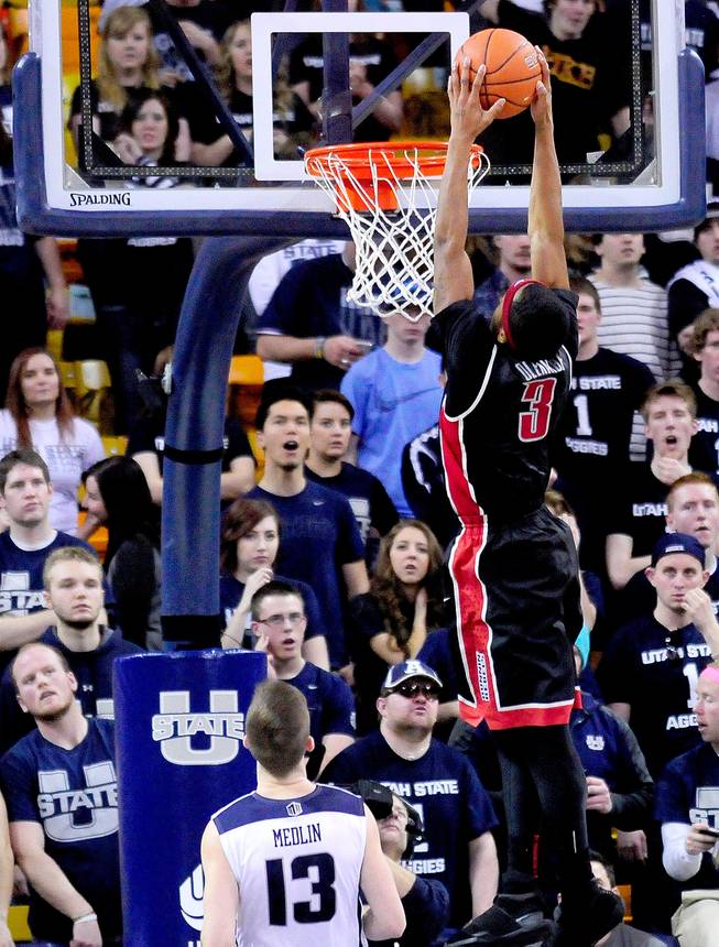 UNLV's Kevin Olekaibe (3) dunks the ball over Utah State's Preston Medlin during an NCAA college basketball game on Saturday, Feb. 15, 2014, in Logan, Utah.